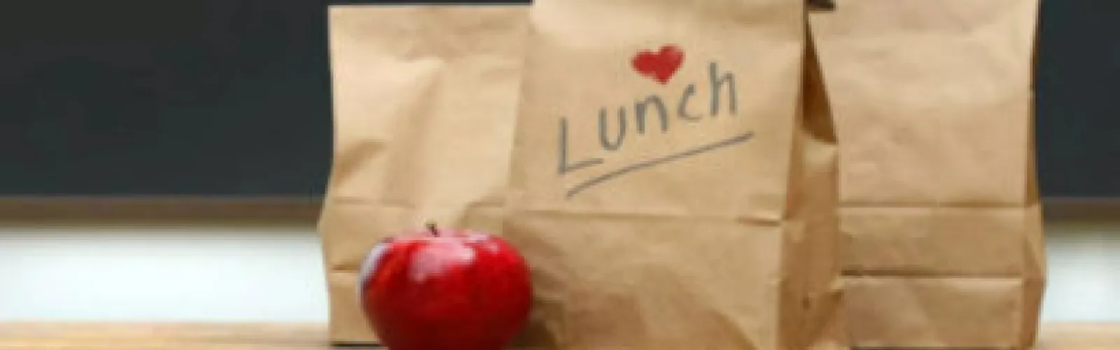 Three lunch bags with an apple. The front lunch bag is labeled Lunch and has a heart on it.